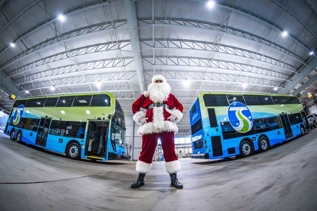 Santa Claus standing in front of two STA double-decker buses inside the Boone NorthWest Garage